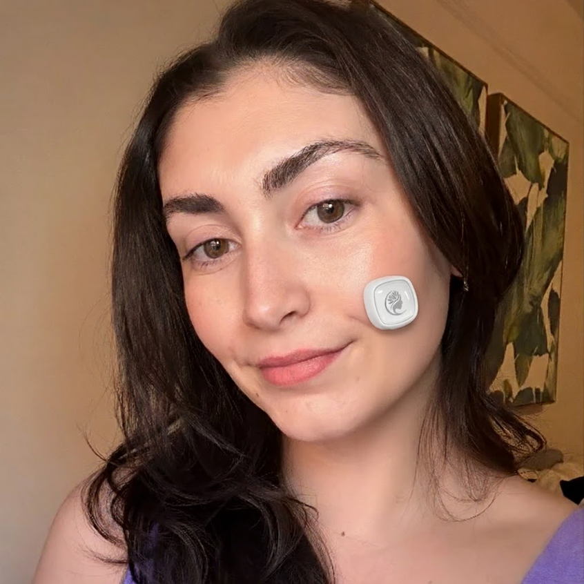 Woman wearing Viva Glam Acne Light Therapy patch on her face with a neutral background