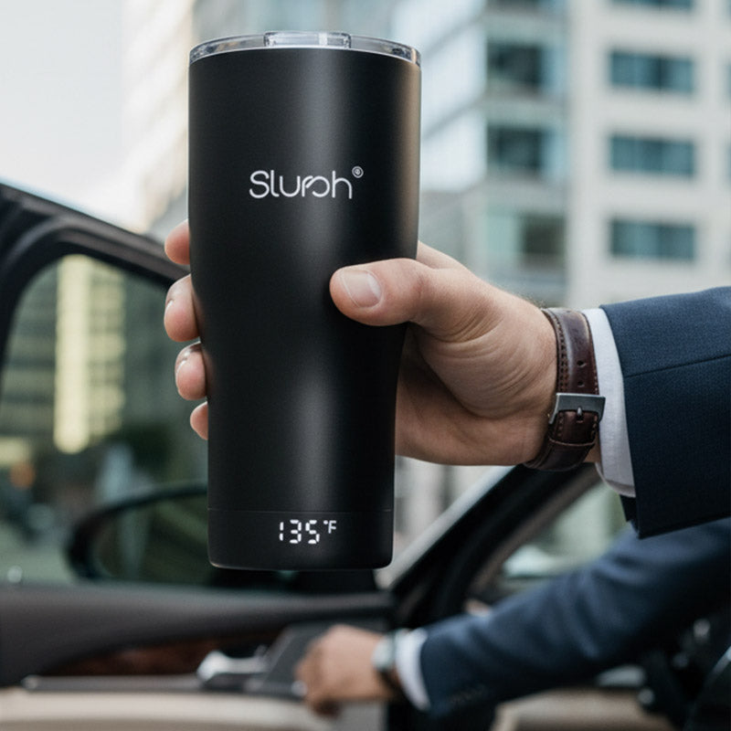 Person holding a black Slursh smart temperature control tumbler with digital temperature display in a car.